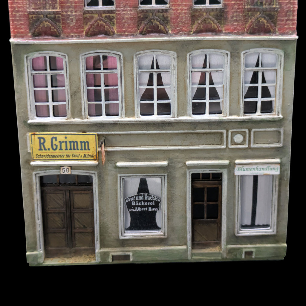 Nahaufnahme der unteren Fassade mit Fenstern, Türen und Beschriftung.