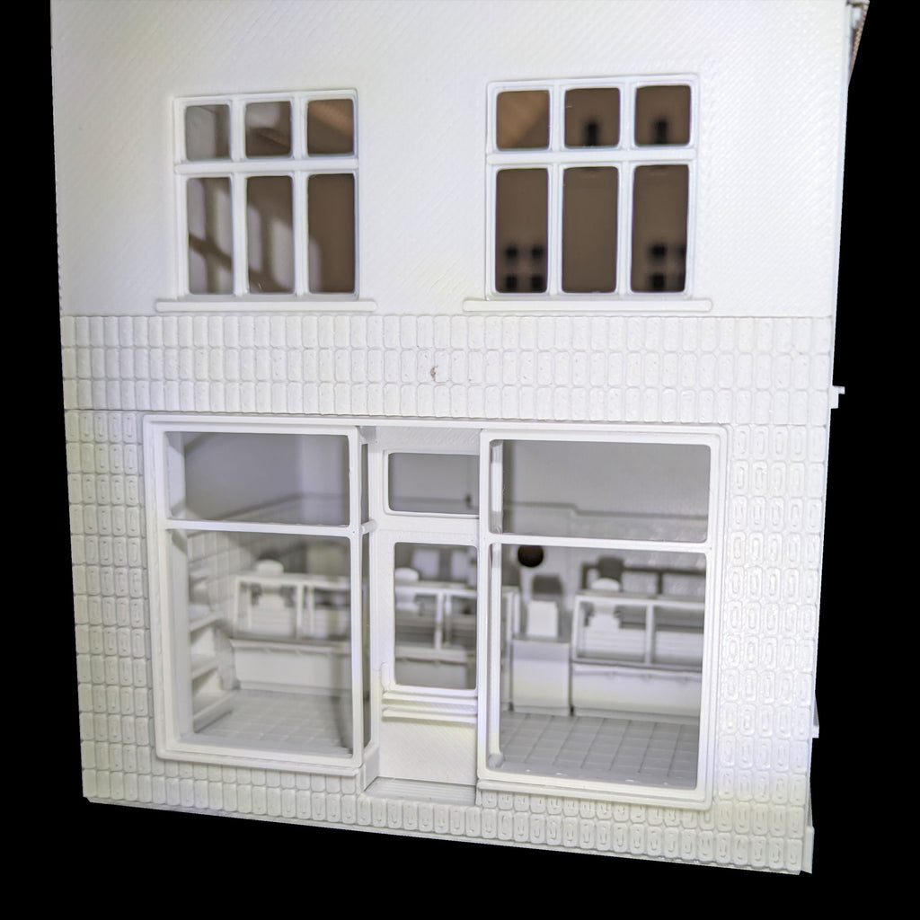 Nahaufnahme der großen Schaufenster des H0 Ladenmodells mit Blick auf die Verkaufstheken.