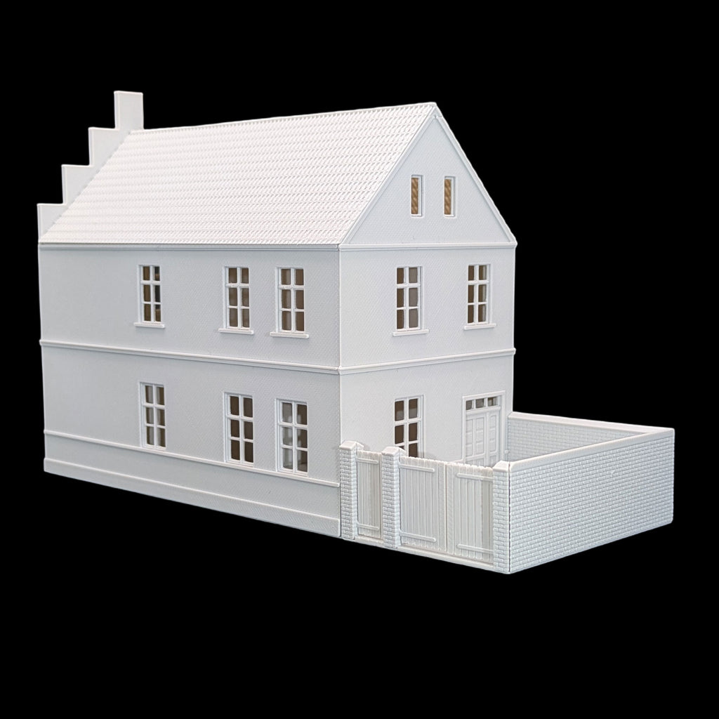 Seitenansicht des TT Stadthauses mit Fenstern, weißer Fassade und ummauertem Hofbereich.